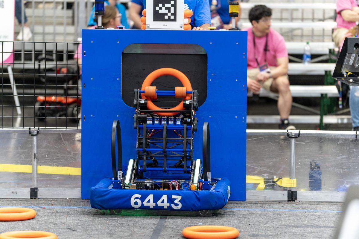The built 2024 robot on the field with a game piece loaded in the shooter