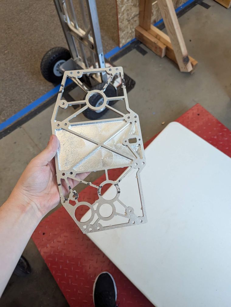 A finished pocketed aluminium plate held in hand, lightened with a triangular rib pattern